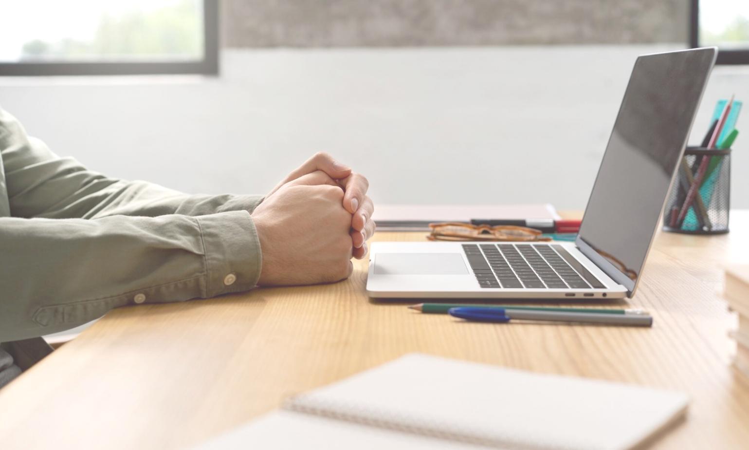 Person arbeitet konzentriert an Finanzplanung mit Laptop und Unterlagen